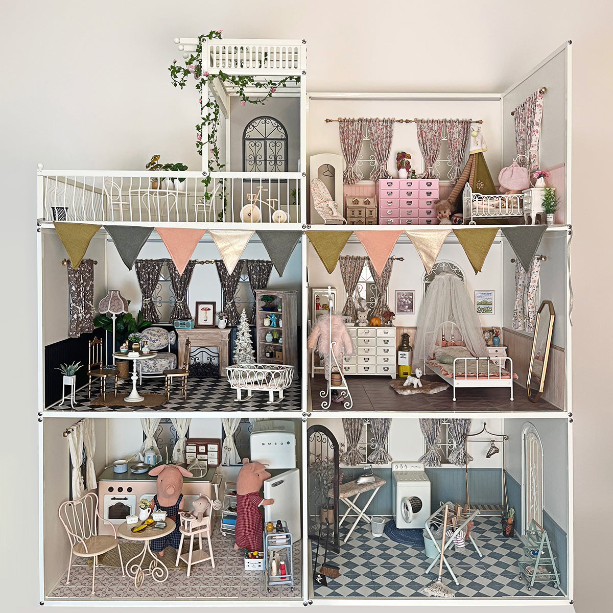 Multiroom dollhouse display with the pink-canopy baby cot in the upper-right nursery and other miniature furniture, dolls and decorative accessories shown as styling props
