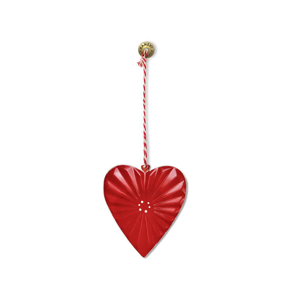 Red metal heart Christmas ornament with ridged surface, small gold dots, hanging cord and metal disc on a white background